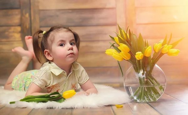 Uma criança pequena com um buquê de tulipas amarelas. Um rapaz com um dom — Fotografia de Stock