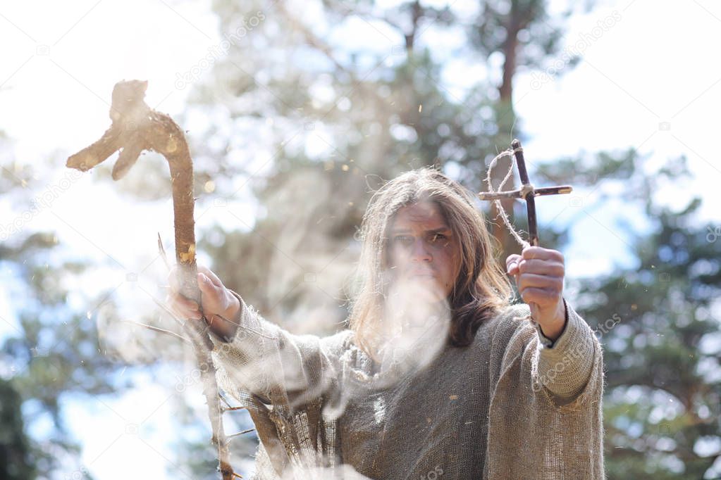 A man in a cassock spends a ritual in a dark forest