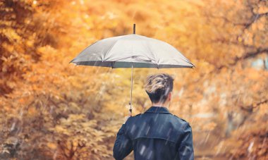 Sonbahar yağmurlu hava ve bir şemsiye ile genç bir adam