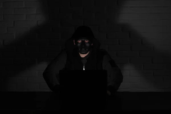 Hacker în mască neagră și capotă la masă — Fotografie, imagine de stoc