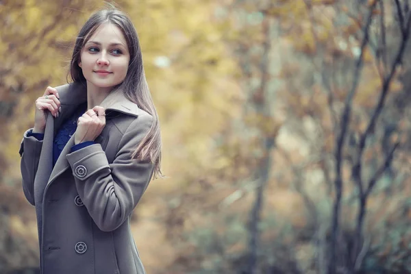 Młoda dziewczyna w płaszczu w jesiennym parku — Zdjęcie stockowe