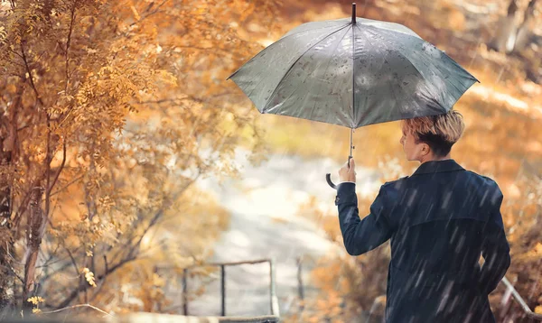 Regniga höstväder och en ung man med ett paraply — Stockfoto