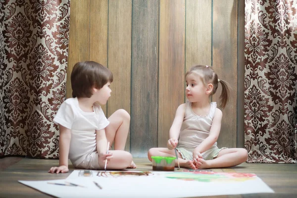 Niños pequeños pintan en una hoja grande de papel —  Fotos de Stock