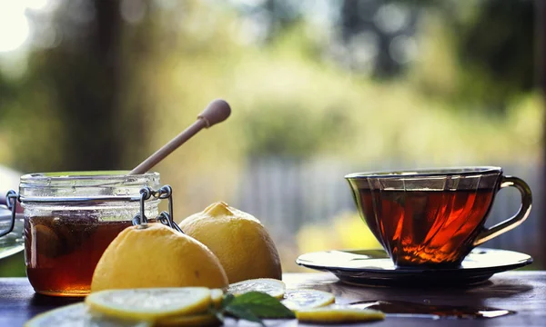 Tea with lemon and mint in nature. A cup of hot mint tea with le