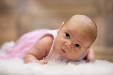 Yeni doğmuş şirin bebek beyaz kürkün üzerinde yatıyor.