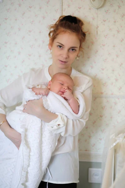 Pretty young mother holding a newborn daughter in arms — Stock Photo, Image