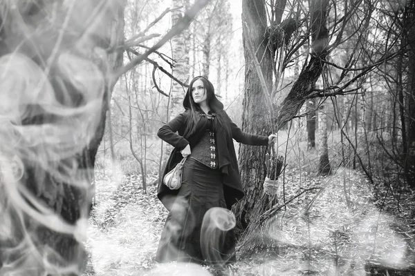 Kvinna i en häxa kostym i en tät skog — Stockfoto
