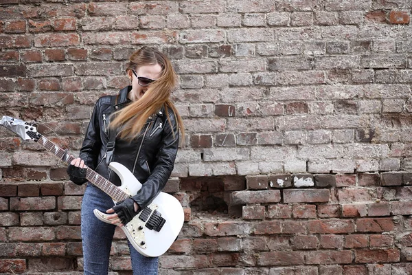 Uma menina músico de rock em uma jaqueta de couro com uma guitarra — Fotografia de Stock