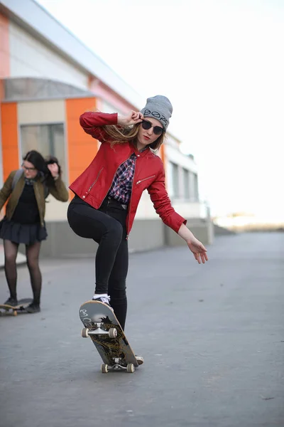 Ένα νεαρό hipster κορίτσι είναι ιππασίας ένα skateboard. Κορίτσια φίλες f — Φωτογραφία Αρχείου