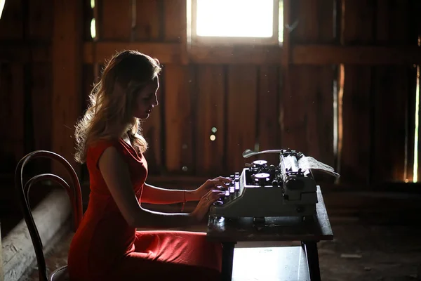 A girl in retro style prints on an old typewriter — Stock Photo, Image