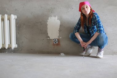 Kız dairede tamirat yapıyor. Eve yeni bir daireye taşınıyor. İşçi onarım, sıvalı yapar ve duvar matkaplar.