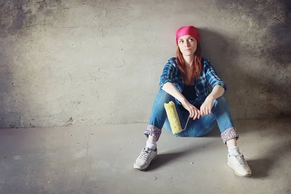 La chica está haciendo reparaciones en el apartamento. Casa mudándose a un nuevo apartamento. El trabajador hace reparaciones, enlucido y taladra la pared . — Foto de Stock