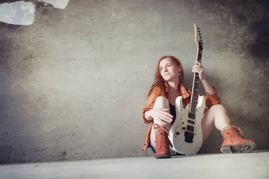 Kızıl saçlı kız bir elektro gitar ile. Rock müzisyen GIR