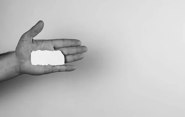 Kis fehér darab papír a kezében ember monokróm — Stock Fotó