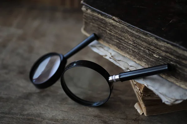 Libros antiguos sobre una mesa de madera y lupa — Foto de Stock