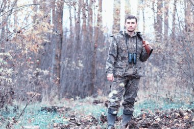 Kamuflaj ve bir sp üzerinde bir ormanda bir av tüfeği ile bir adam