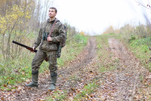 Людина в камуфляжі і зі зброєю в лісовому поясі на весняному полюванні — стокове фото