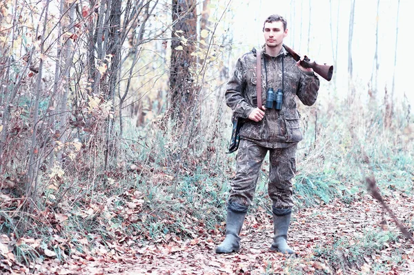 Un hombre en camuflaje y con un rifle de caza en un bosque en una sp —  Fotos de Stock