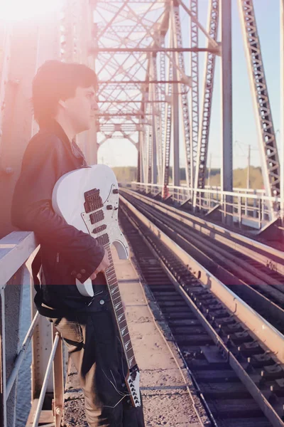 Un hombre con una guitarra eléctrica en el ferrocarril. Un músico en una le — Foto de Stock