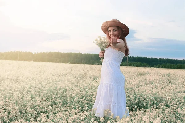 Chica en vestido blanco en un campo de flores amarillas floreciendo — Foto de Stock