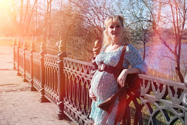 Une fille enceinte en promenade dans le parc. Fille avec un ventre dans le ci — Photo