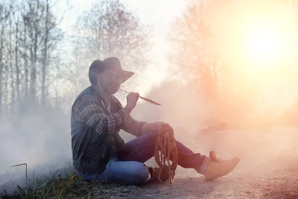 Um homem está usando um chapéu de cowboy e um loso no campo. Americano — Fotografia de Stock