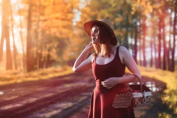 En flicka i en hatt på en promenad i parken. En flicka med en korg promenad — Stockfoto