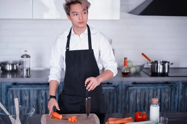 Asian cook in the kitchen prepares food in a cook suit