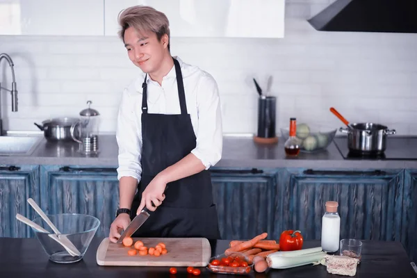 Asian cook in the kitchen prepares food in a cook suit