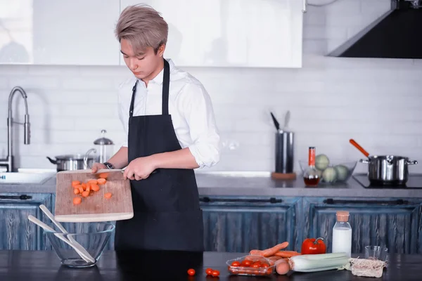 Asian cook in the kitchen prepares food in a cook suit