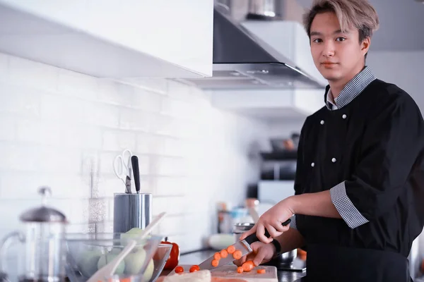 Asian cook in the kitchen prepares food in a cook suit