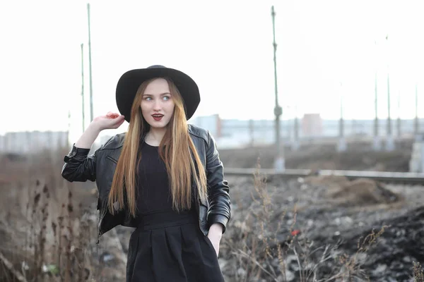 Una ragazza cammina lungo la strada della città in un gilet di pelle con un — Foto Stock