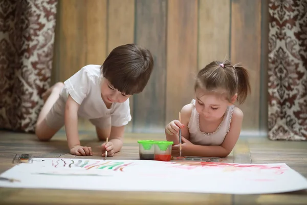 Pequenas crianças pintam em uma grande folha de papel — Fotografia de Stock