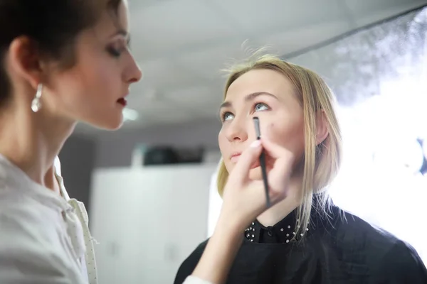 Ung flicka med en make-up artist — Stockfoto