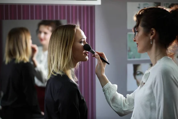 Ung flicka med en make-up artist — Stockfoto