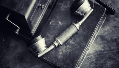 Eski telefon ve retro kitap masanın üzerinde. Geçmişte telefon 