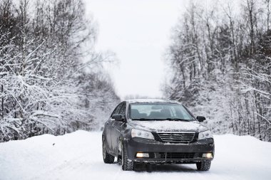 Bir karla kaplı yolda araba duruyor