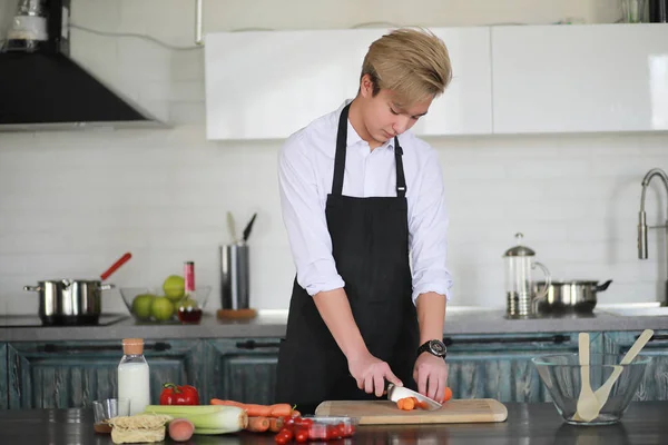 Asian cook in the kitchen prepares food in a cook suit