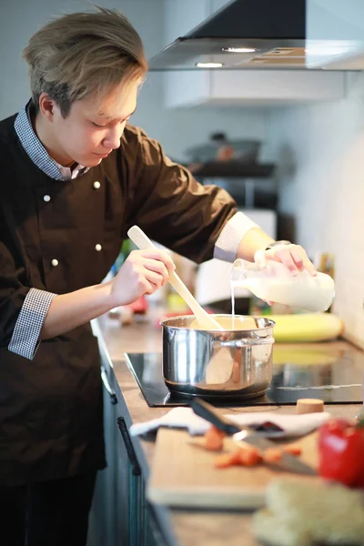 Asian cook in the kitchen prepares food in a cook suit