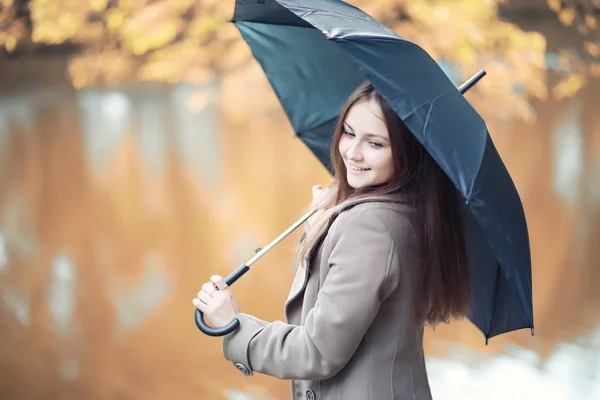 Chica joven en un abrigo en el parque de otoño — Foto de Stock