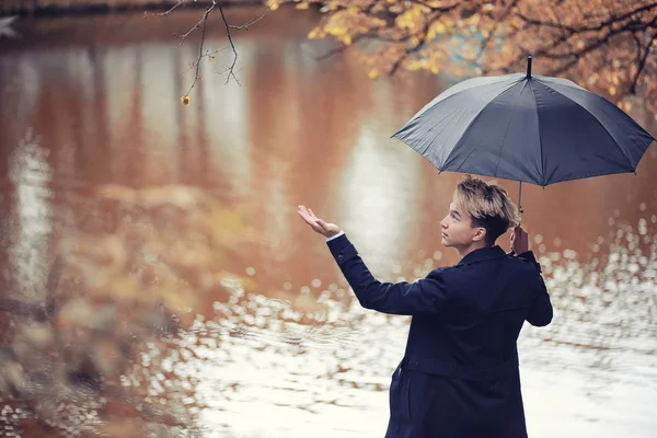 Sonbahar yağmurlu hava ve bir şemsiye ile genç bir adam — Stok fotoğraf