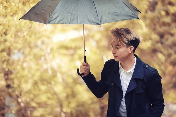 Automne temps pluvieux et un jeune homme avec un parapluie — Photo