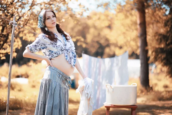 Pregnant woman hanging sheets on the rope for drying — Stock Photo, Image