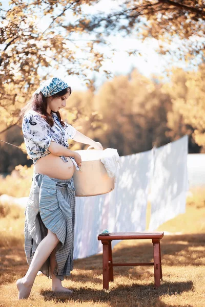 Pregnant woman hanging sheets on the rope for drying — Stock Photo, Image