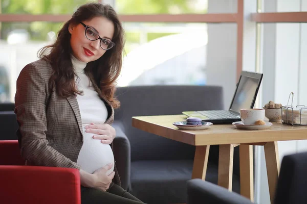 Mujer embarazada trabajando en la computadora en la cafetería — Foto de Stock