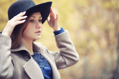 Sonbahar parkında montlu genç kız.