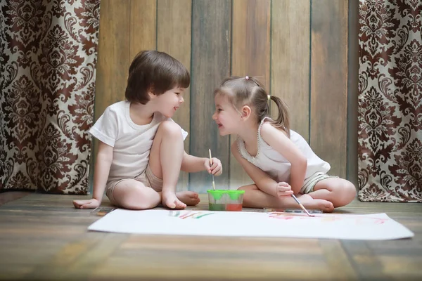 Niños pequeños pintan en una hoja grande de papel —  Fotos de Stock