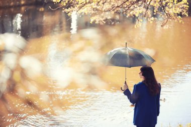 Hamile bir kadın parkta yürüyor.