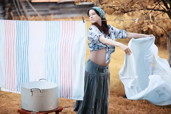 Pregnant woman hanging sheets on the rope for drying — Stock Photo, Image