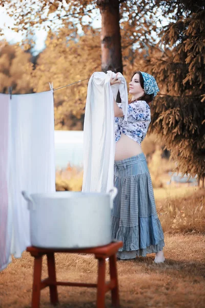 Pregnant woman hanging sheets on the rope for drying — Stock Photo, Image